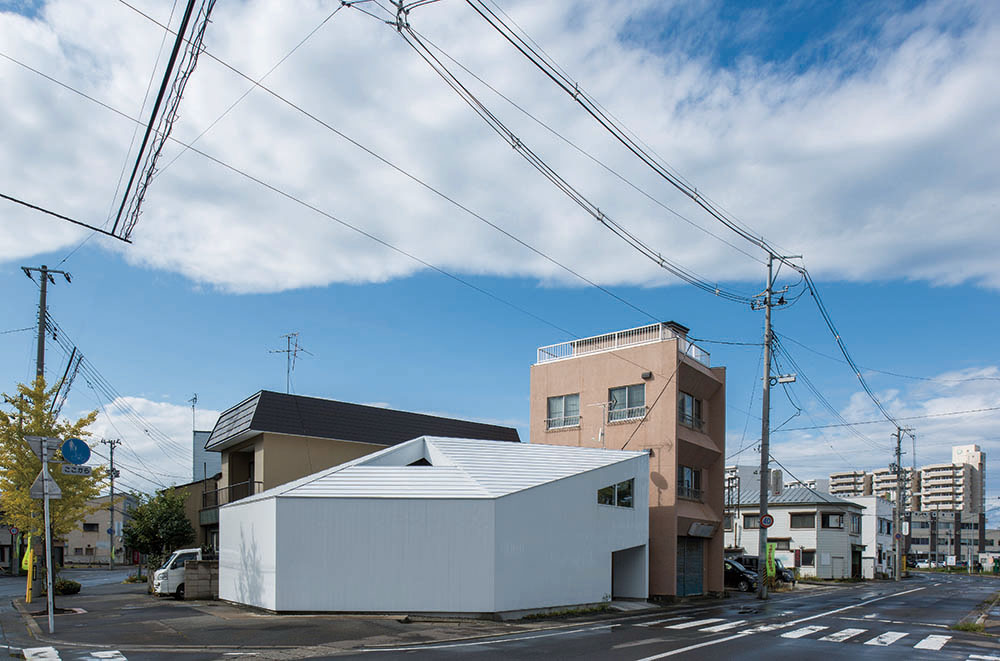 目立った窓がなく、五角形の白い箱のような外観。三面は道路、二面は住宅に囲まれている。屋根には雪止めを設けて落雪を防ぎ、三角に開いた部分は中庭となっている