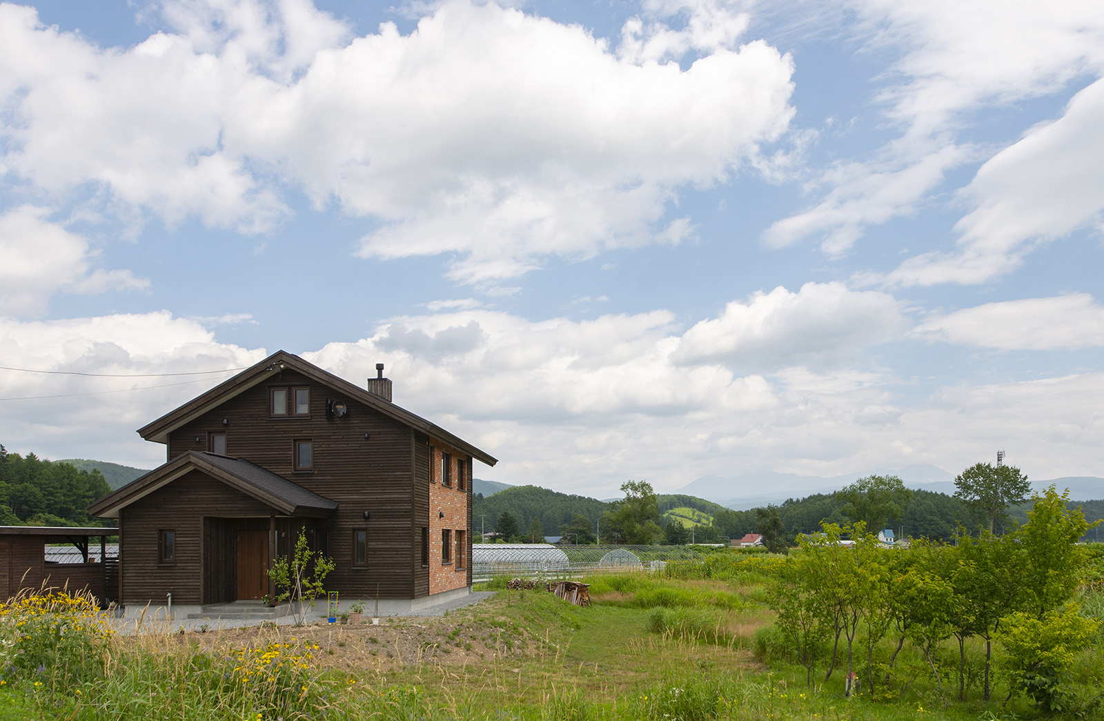 周りの景色に溶け込む外観。外壁に使ったトドマツは加工が施してあり、年月とともに味のある風合いになる。一部レンガ張りの部分にはツル系の植物を這わせる予定