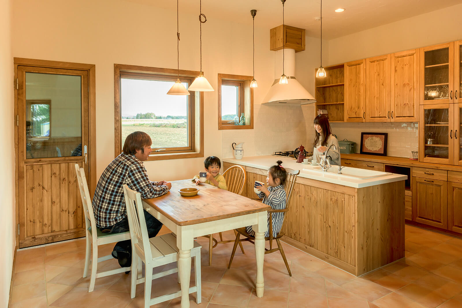 家族が集うダイニング・キッチンには、パイン材を用いて造作したキッチンと食器棚、食品庫、低温庫を設置。オリジナル木製サッシで切り取られた田園風景も、インテリアの一部に