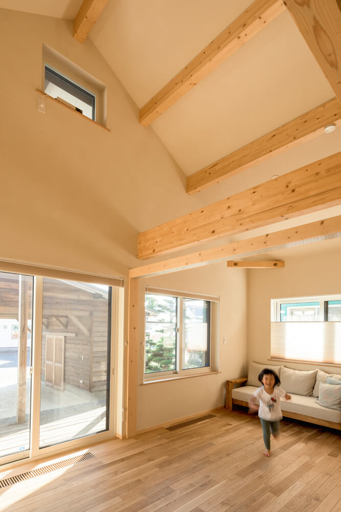 三角屋根の形状を生かした高い天井が心地よいリビング。高窓は夏の熱気抜きに役立つ