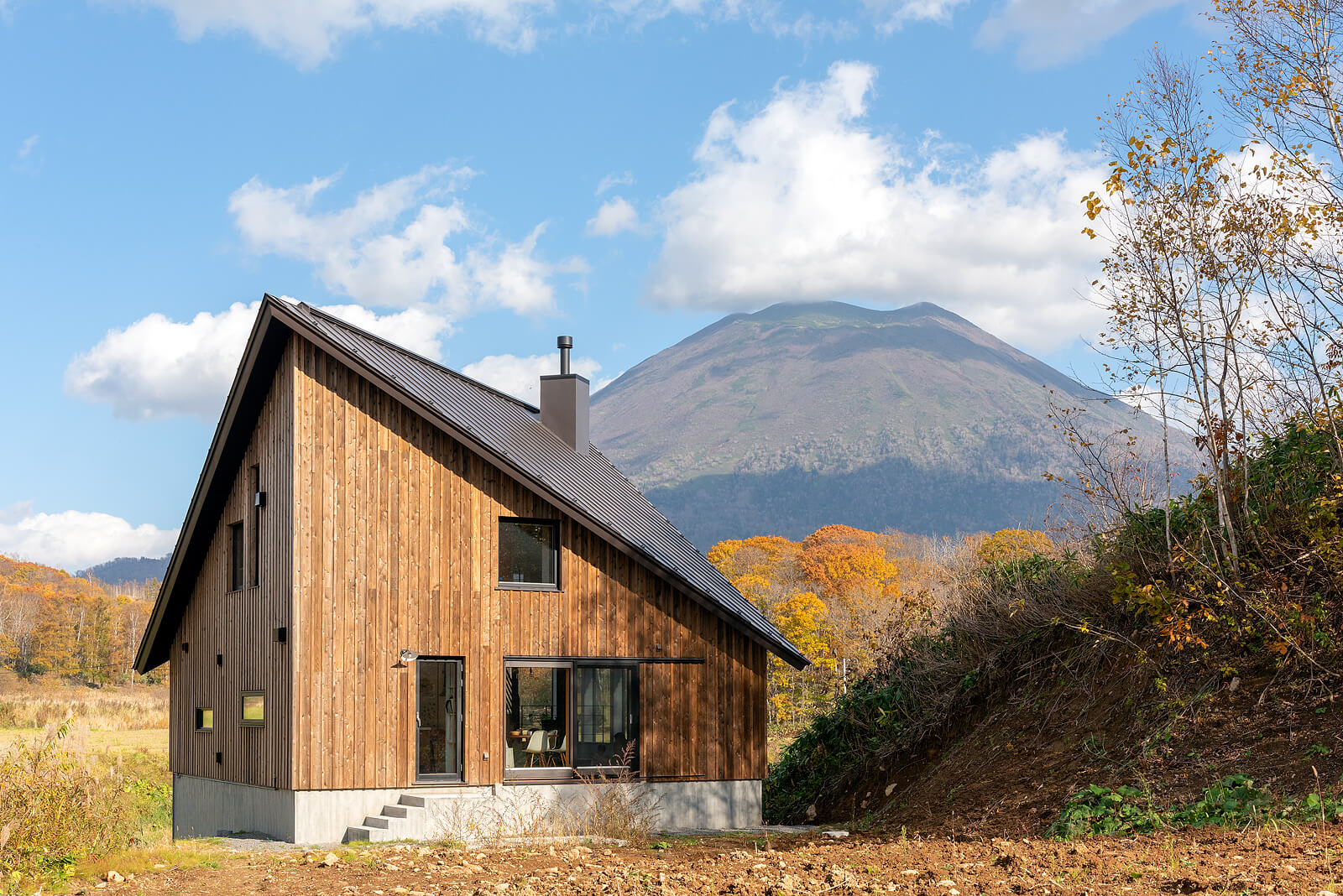 背景に羊蹄山の景色が広がるNさん宅。アプローチと反対側から見ると2階建てのよう。傾斜地を生かしていることがわかる