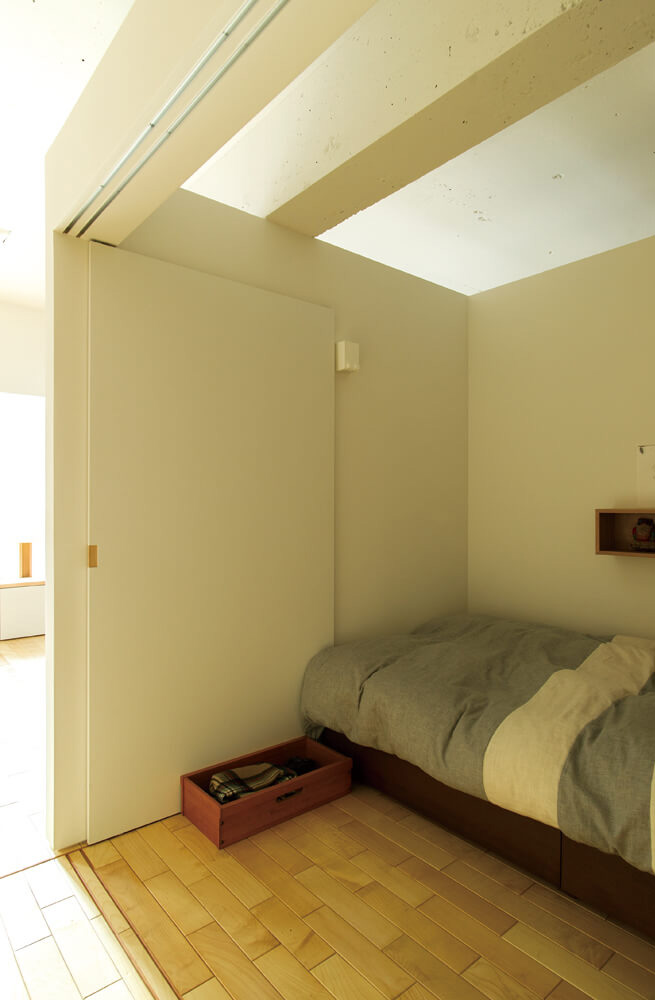 寝室は引き戸を開ければ開放的に。天井もあえて壁で仕切らずリビングとつながる空間にした