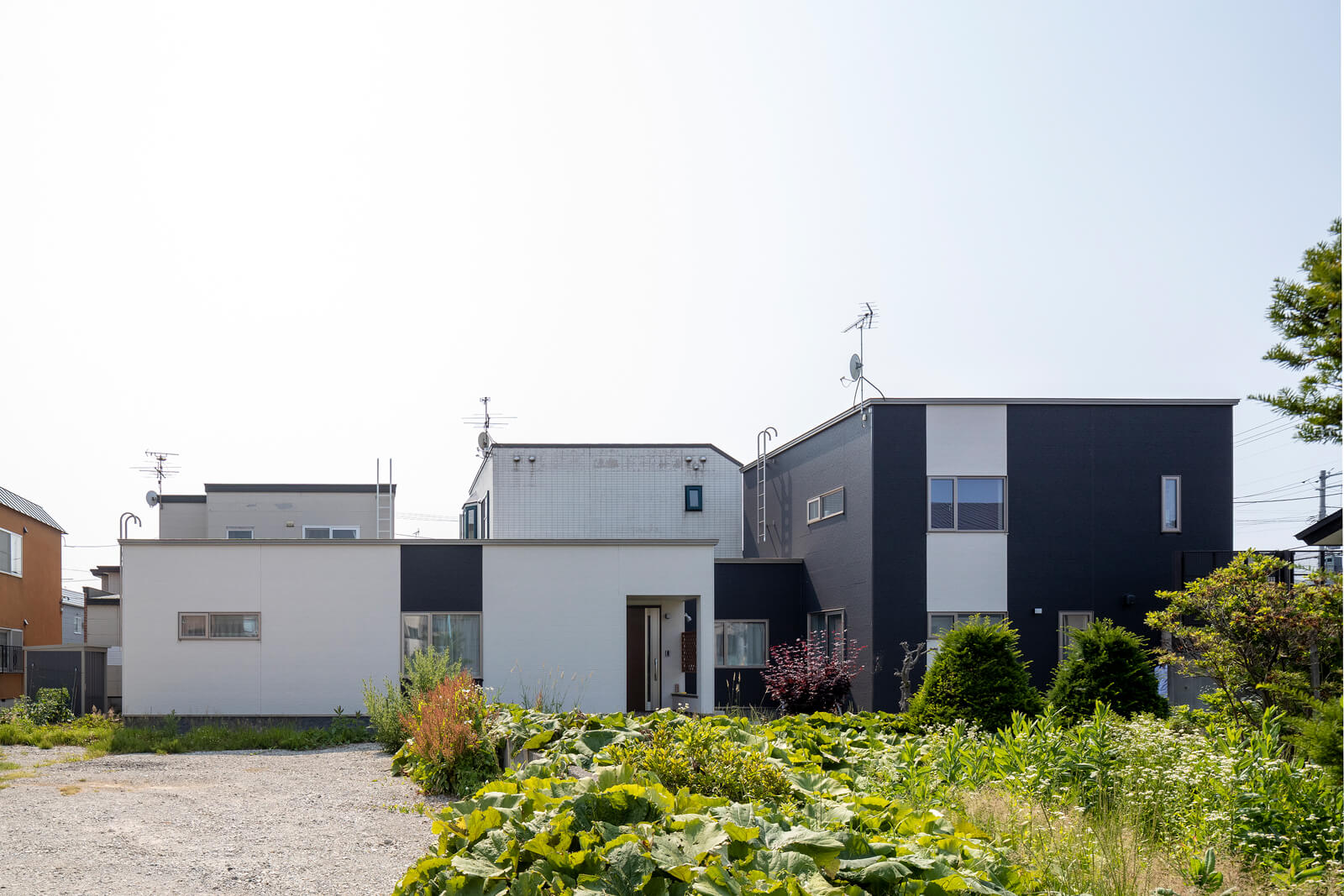 細長い敷地の形状を生かし、奥側（写真左）には平屋の親世帯の住まいを、道路側（写真右）には2階建てのFさんご家族の住まいを配置している