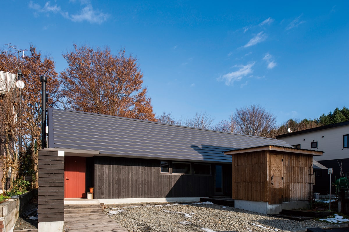 紅葉を背に建つ三角屋根の平屋の住まい。「納屋のような素朴な雰囲気にしたかった」とWさん