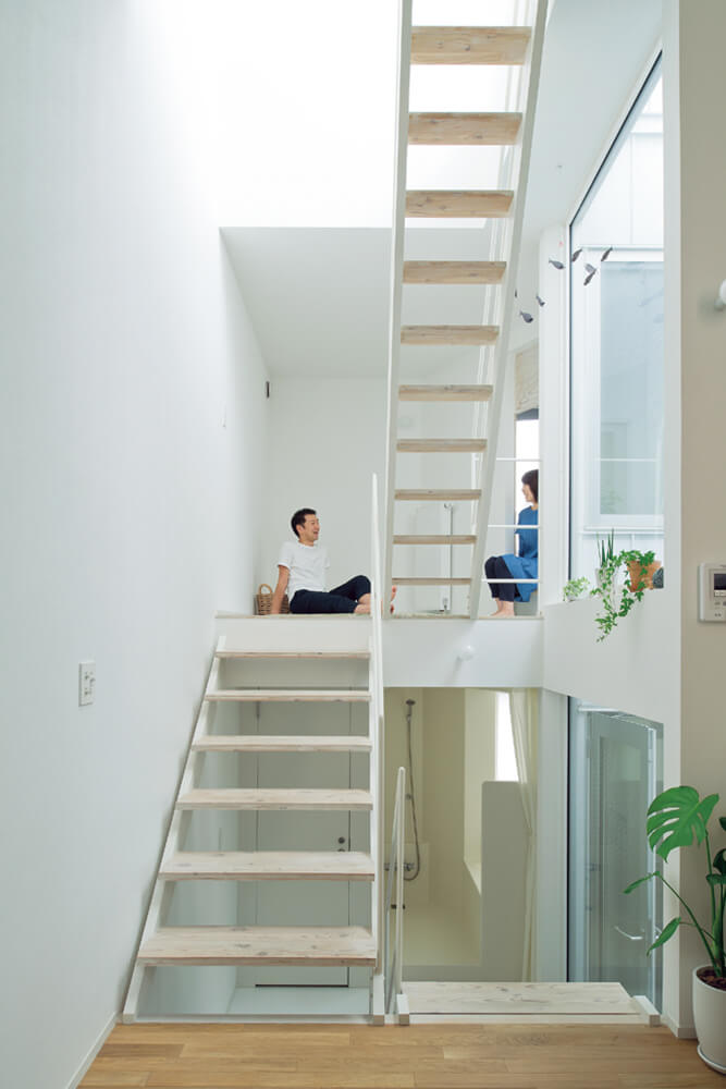 階段の踊り場が部屋になっているスキップフロアの住まい。左の壁から階段の右にある大開口までの距離はなんと２mしかないが、奥行きと高さのある空間構成で開放的に感じられる。大開口の外は太陽の光と風を室内に届ける光井戸で、外観からは想像がつかないほど室内は明るい