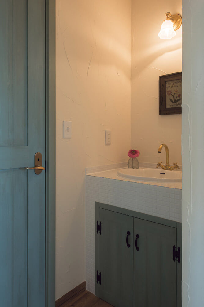 ブルーをアクセントカラーに用いたトイレと造作手洗い。造作の建具や端正な左官仕事で、クラシックな趣に仕上げた