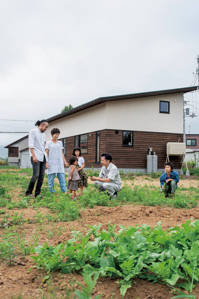 菜園予定地で談笑するYさんご家族と大元社長。「大元社長や友人たちに助けられ、理想の住まいをカタチにすることができました」と奥さん