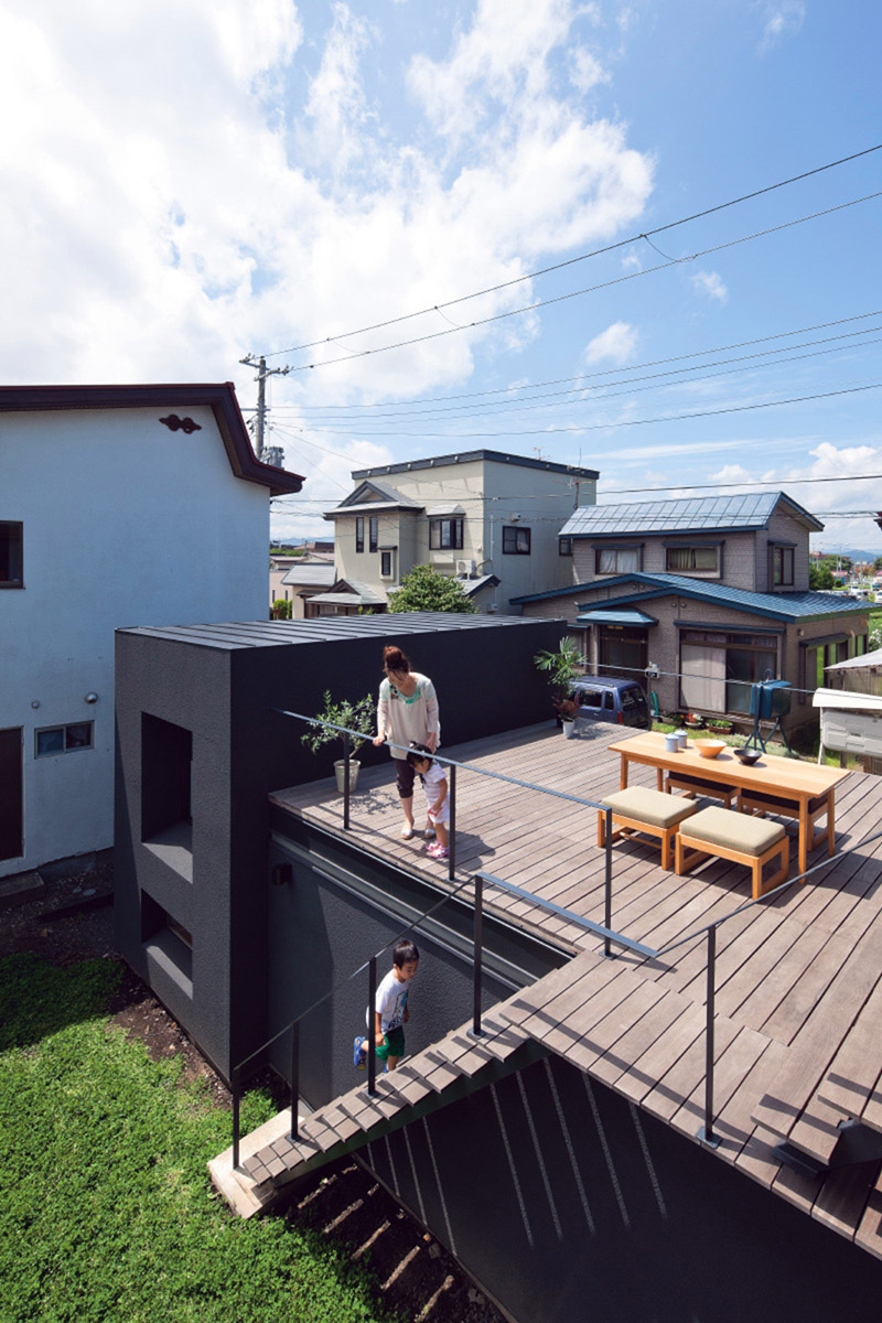 大小の箱を並べた2階建ての住宅。地面から持ち上げられたルーフテラスは周囲と適度な距離感のあるプライベート空間