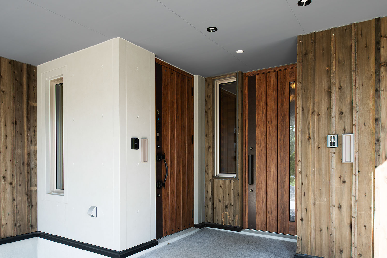 板張り玄関ポーチに合わせて木製ドアを採用した。左側が子世帯、右側がお母さんの住居への入り口