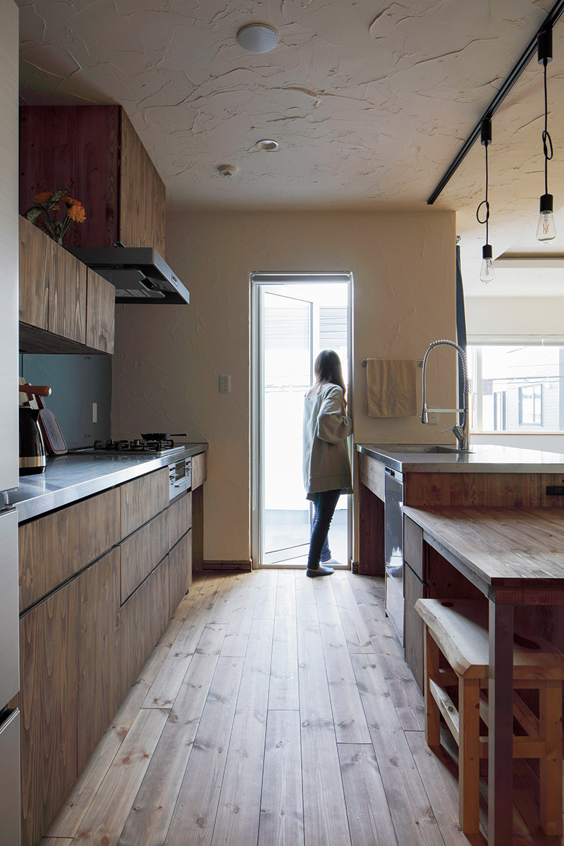 キッチンからバルコニーへの動線。無垢のパイン材の床が美しくまっすぐと伸びる