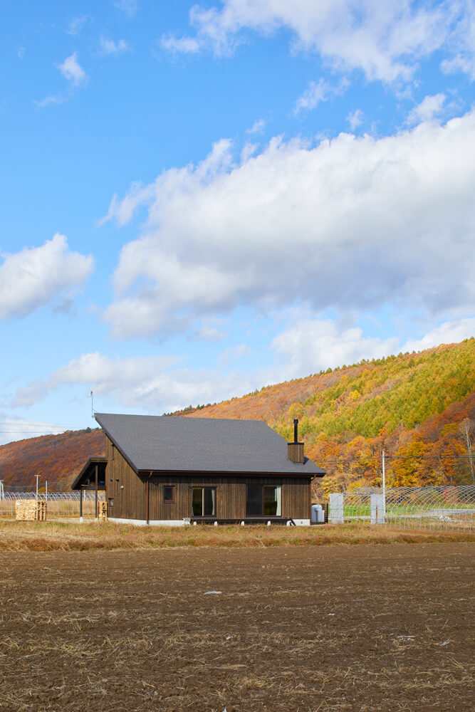 美瑛の田園風景に溶け込むような道南スギ板張りと片流れ屋根のYさん宅。これからリビングとつながるデッキまわりの植栽を整える予定