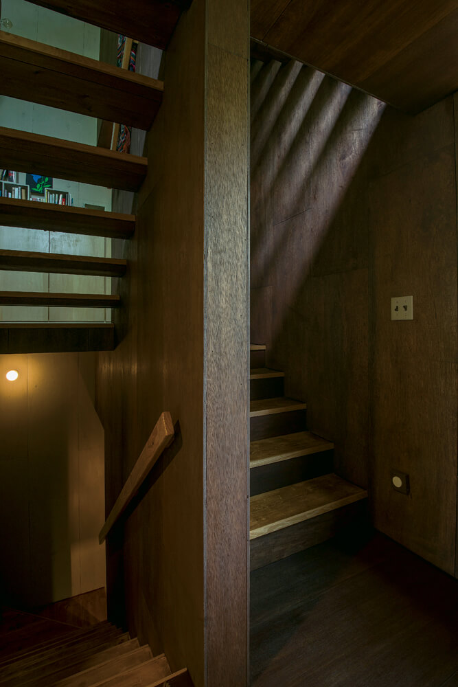 1階の踊り場から階段を見る。踏み板越しの抜けや外からの光が空間の透明感や陰影を生む