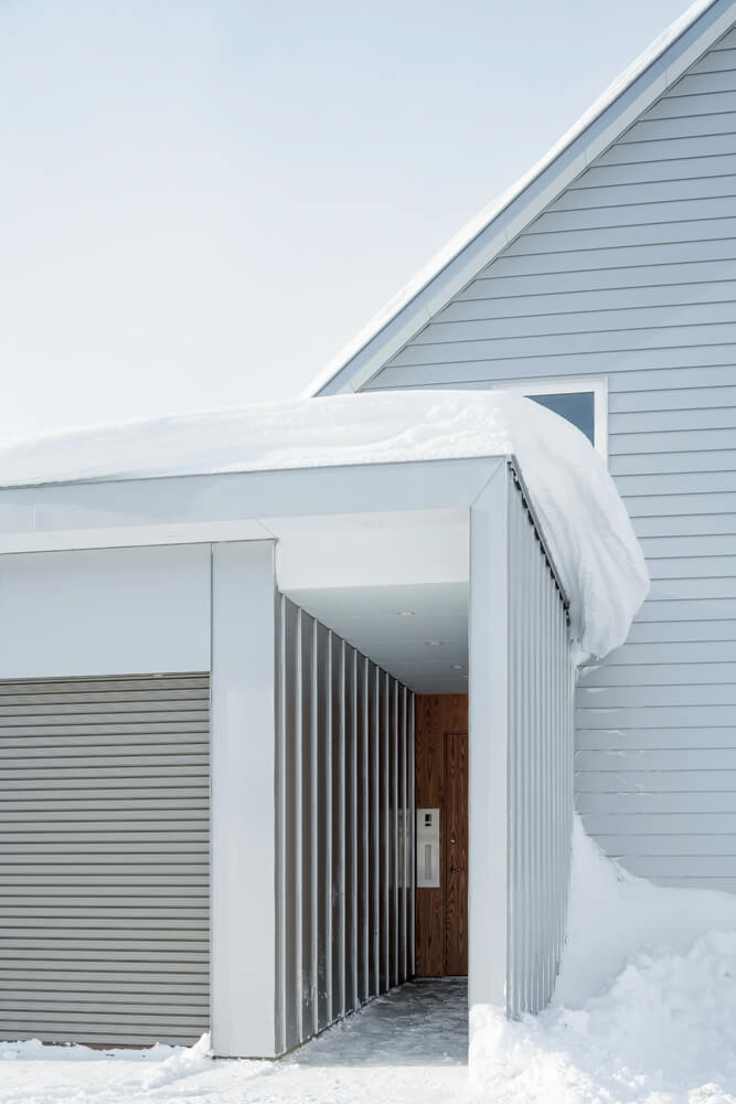 ガレージの建物に組み込んで3方を囲んだアプローチが、吹きすさぶ風雪から家族を守る