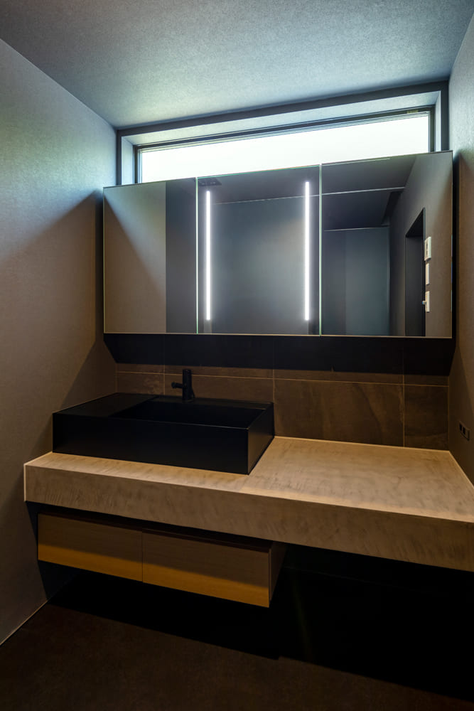脱衣室は黒の洗面ボウルと木の風合い、鏡でスタイリッシュなデザインに