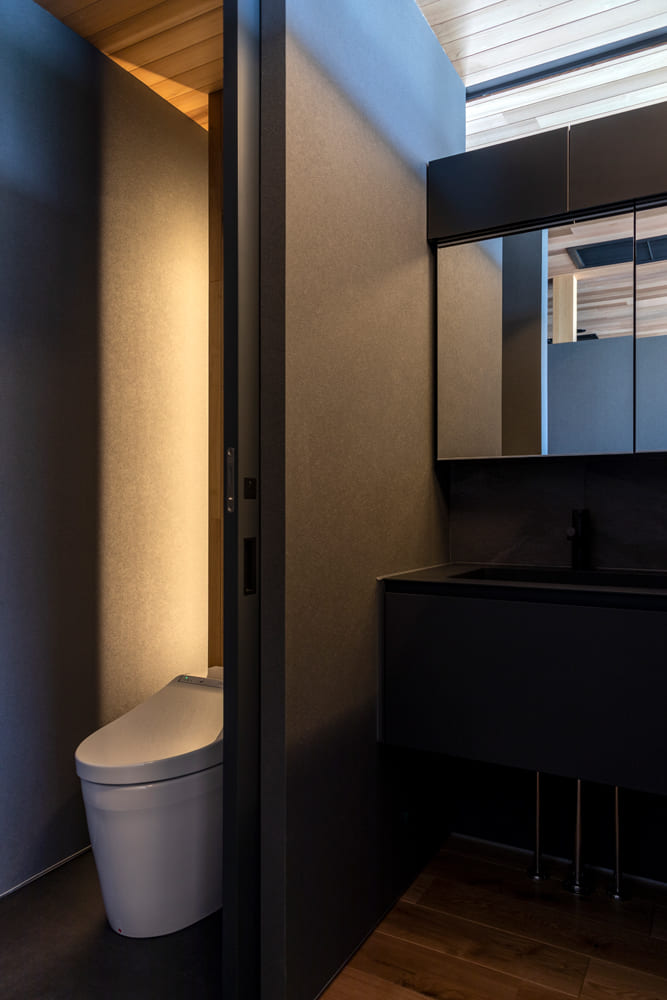 トイレと洗面スペースも黒をベースにシックな佇まい。仕切り壁の上を開けているので光が入る