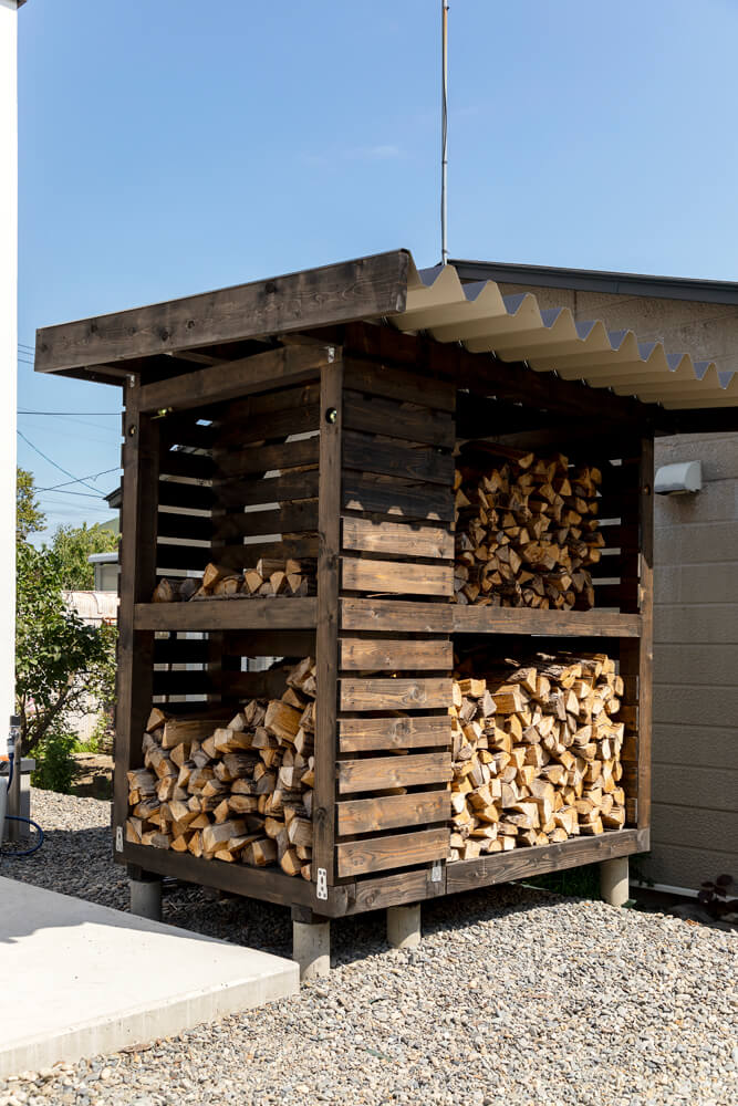 多方向からアクセスができるように配慮した造作の薪小屋。横一列にした薪棚より省スペースで使いやすい