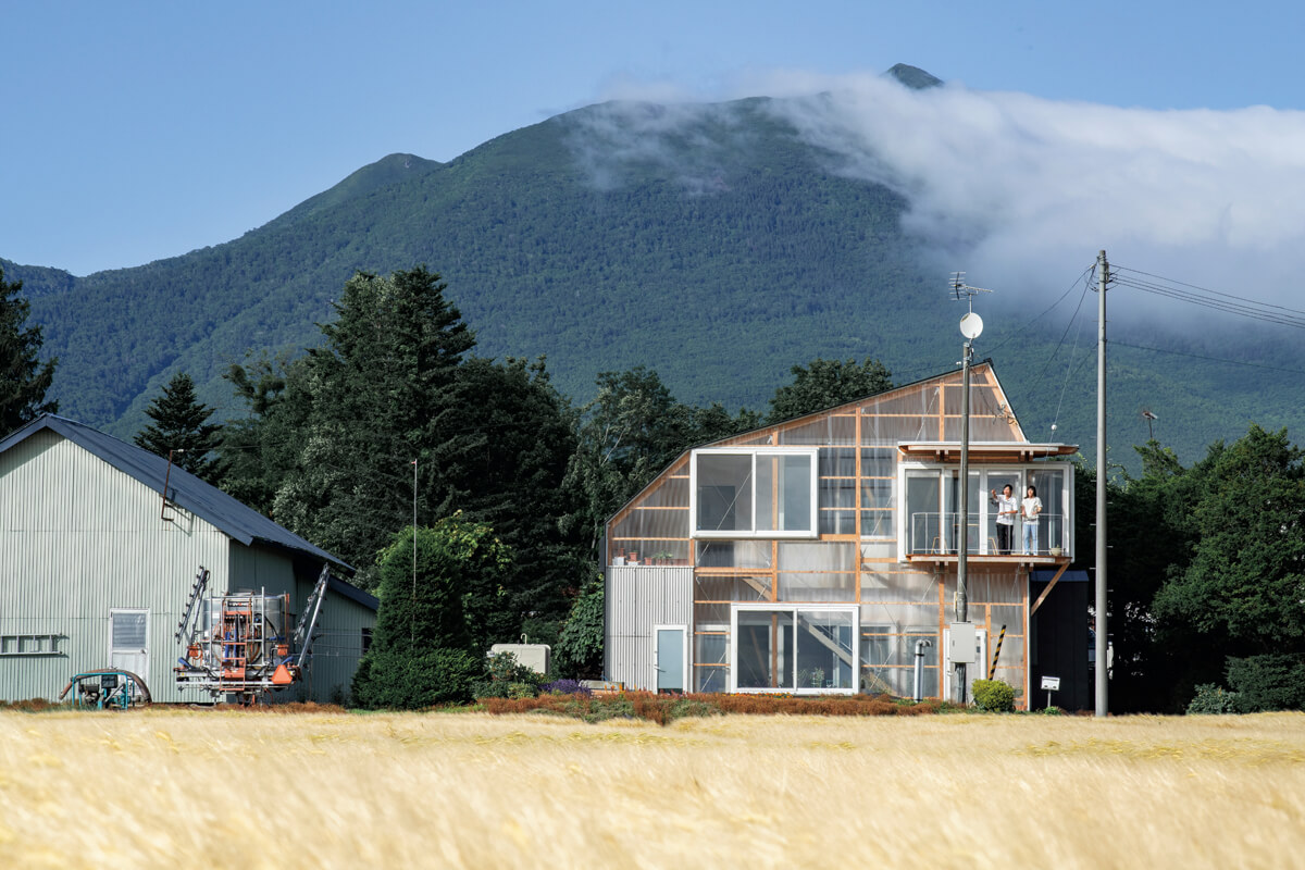 目の前は自宅の畑、背後には山がそびえる絶好のロケーションに建つ農家の2世帯住宅。大麦を育てた今年は、畑一面が柔らかな黄金色に染まった