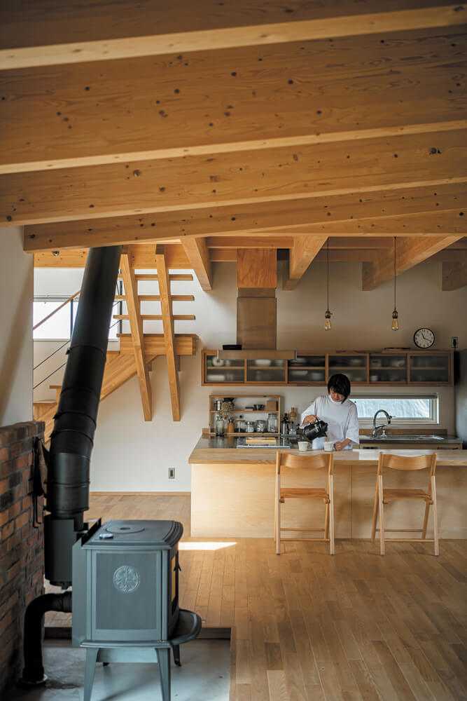こだわりのオーダーメイドキッチンは床レベルを下げて、庭や薪ストーブを眺めやすい高さに設計している