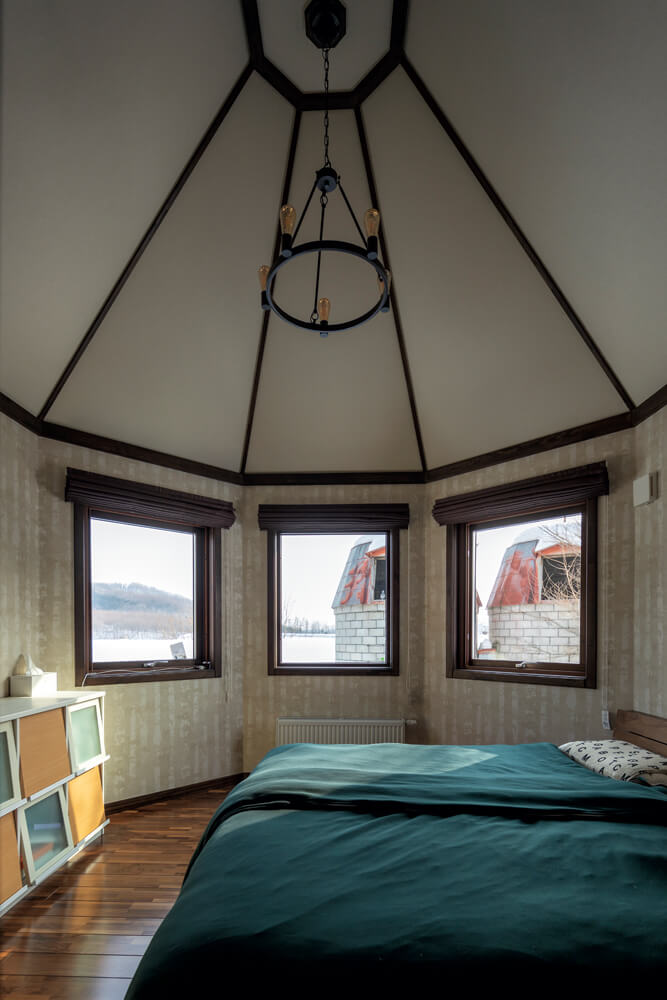 ウォールナットの上品さが漂うご夫妻の寝室は、塔の形に合わせて設えられた3つの窓が印象的