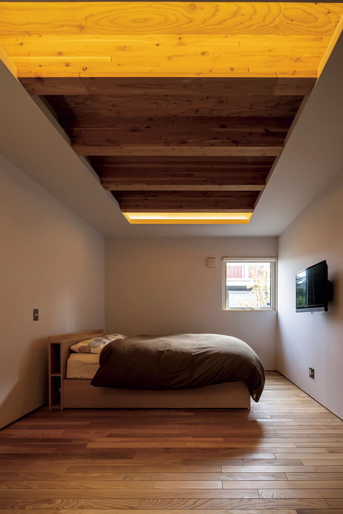 1階に設けた寝室は、窓を小さくして落ち着いた空間。現しの天井からの間接照明の光が優しい