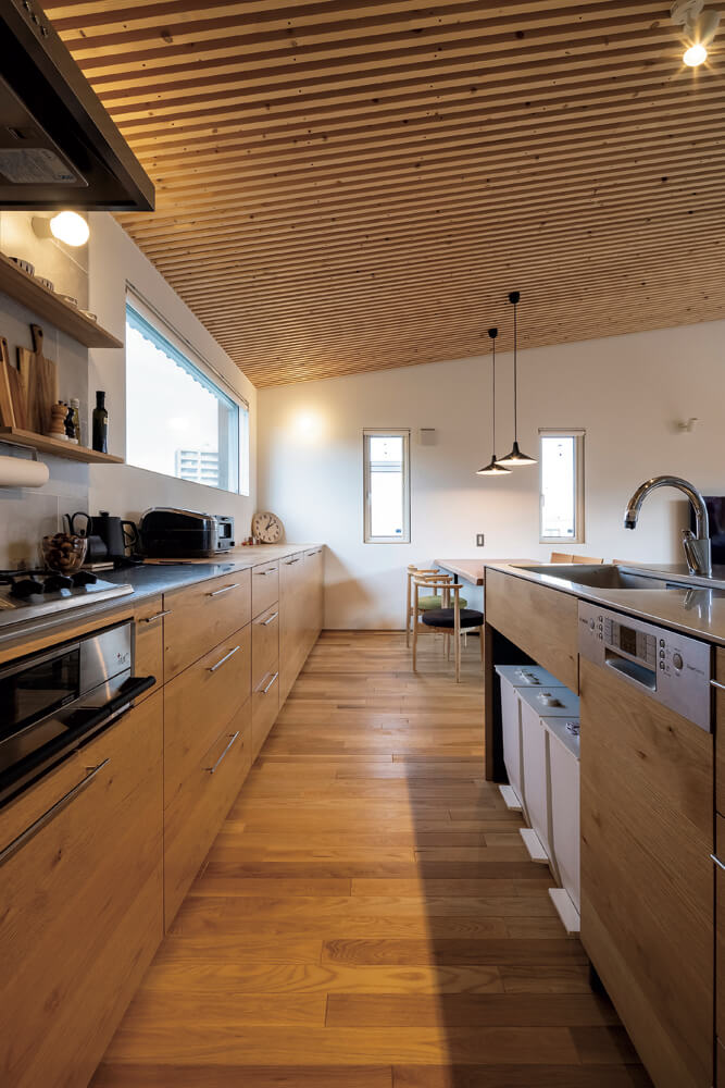 造作のキッチンは壁側にガスコンロと大容量の収納、対面にシンクを備え、家事がしやすい動線に