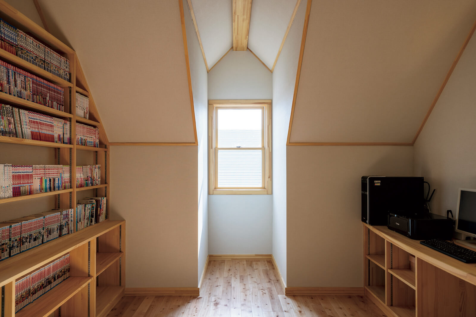 壁一面に本棚を造作した2階のファミリースペースには、三角屋根の傾斜を生かした個性的な出窓