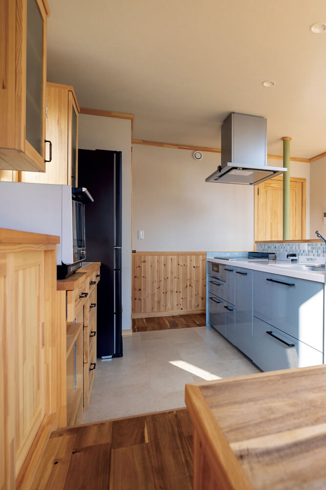 ブルーグレーのキッチンにモザイクタイルがおしゃれ。木製の作業カウンター収納は造作
