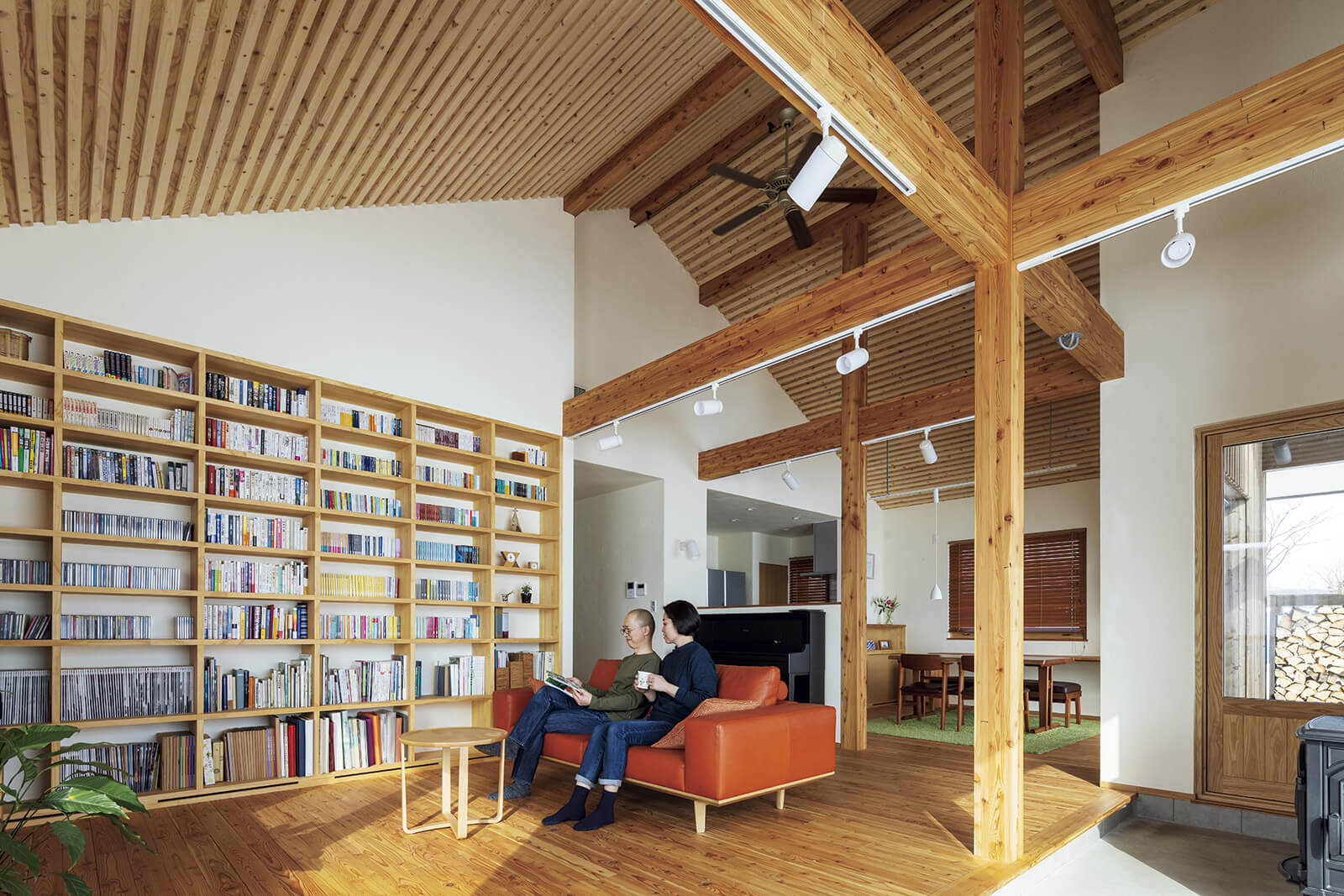 現しの梁が美しい開放的な勾配天井は一番高いところで5.5m。あえて小屋裏をつくらない贅沢なつくり。リビングの壁面いっぱいの本棚は高さ2400㎜、幅3500㎜で家中の書物を収納できる