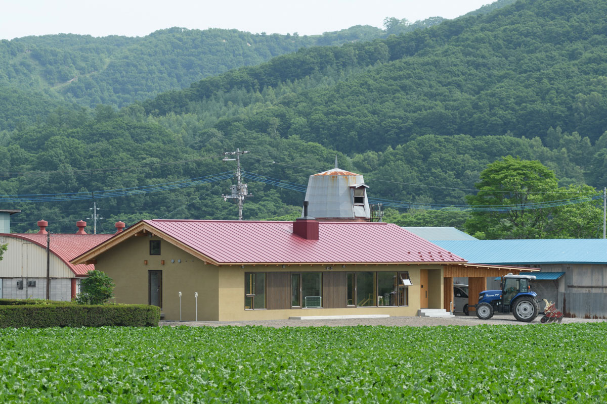 畑の真ん中にあるHさん宅。周囲の風景に自然になじむ黄土色の塗り壁に、レンガ色の赤い屋根が印象的