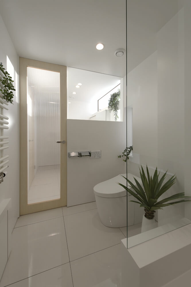 洗面所とトイレの間のドアはポリカーボネート製で、仕切り壁上部はガラス。洗面台や便座の高さに合わせて視線の抜けと遮断を調整し、開放感と使い勝手の良さを両立している