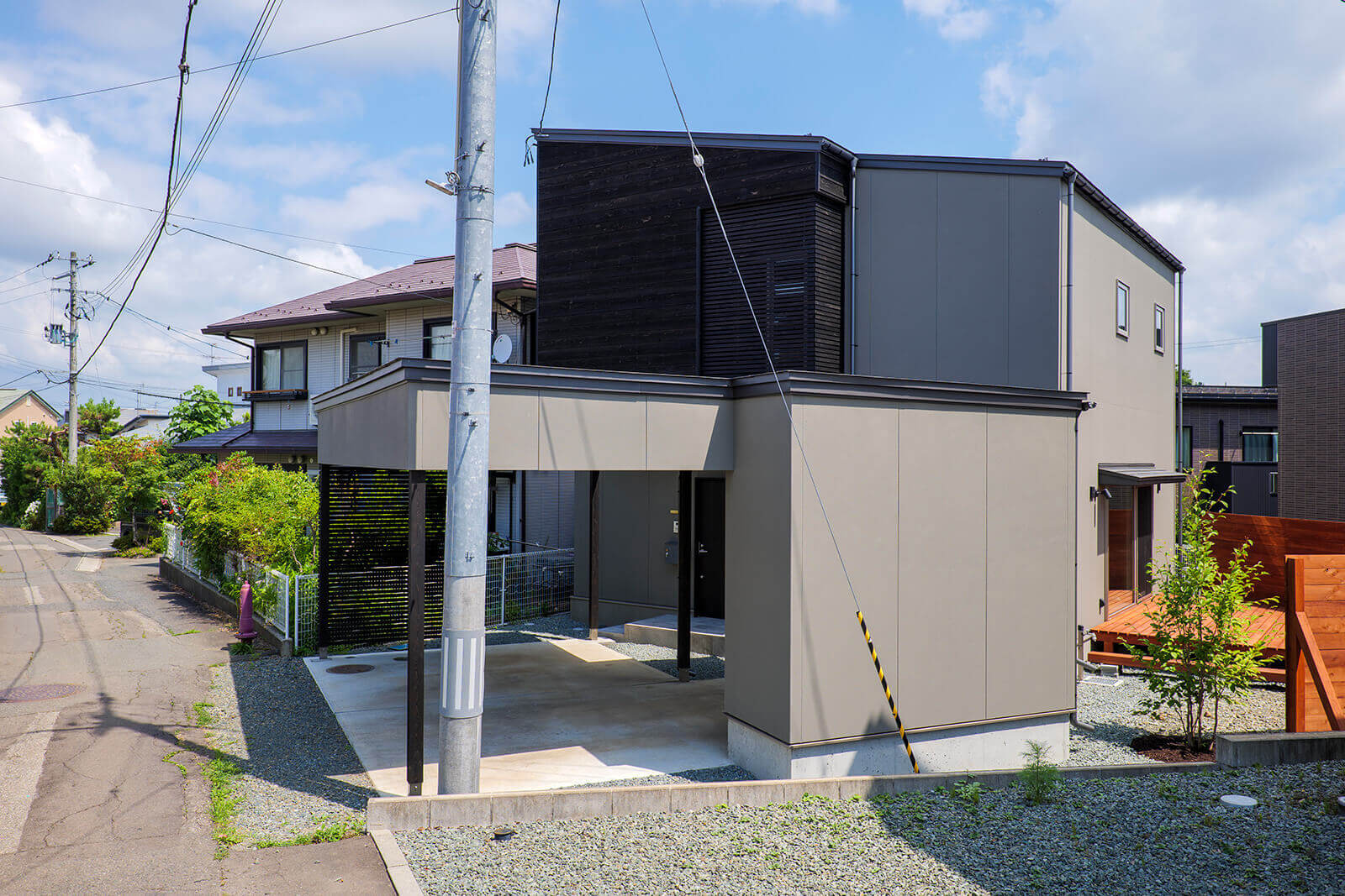 敷地形状により住宅とガレージは角度を振って配置。 空き地を利用しデッキや庭としている