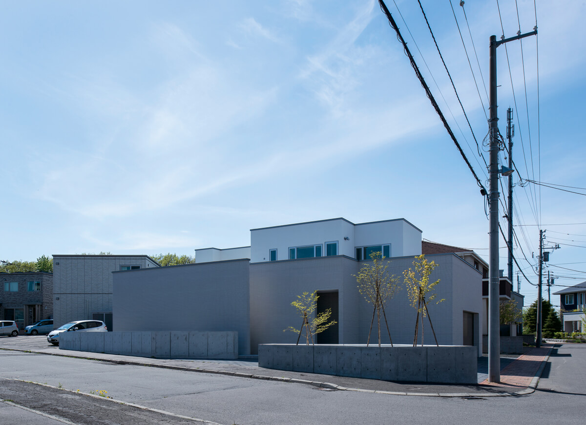 角地に建っているため外観は閉じつつ、景観との緩衝となるようアプローチ部分には植栽を配置した