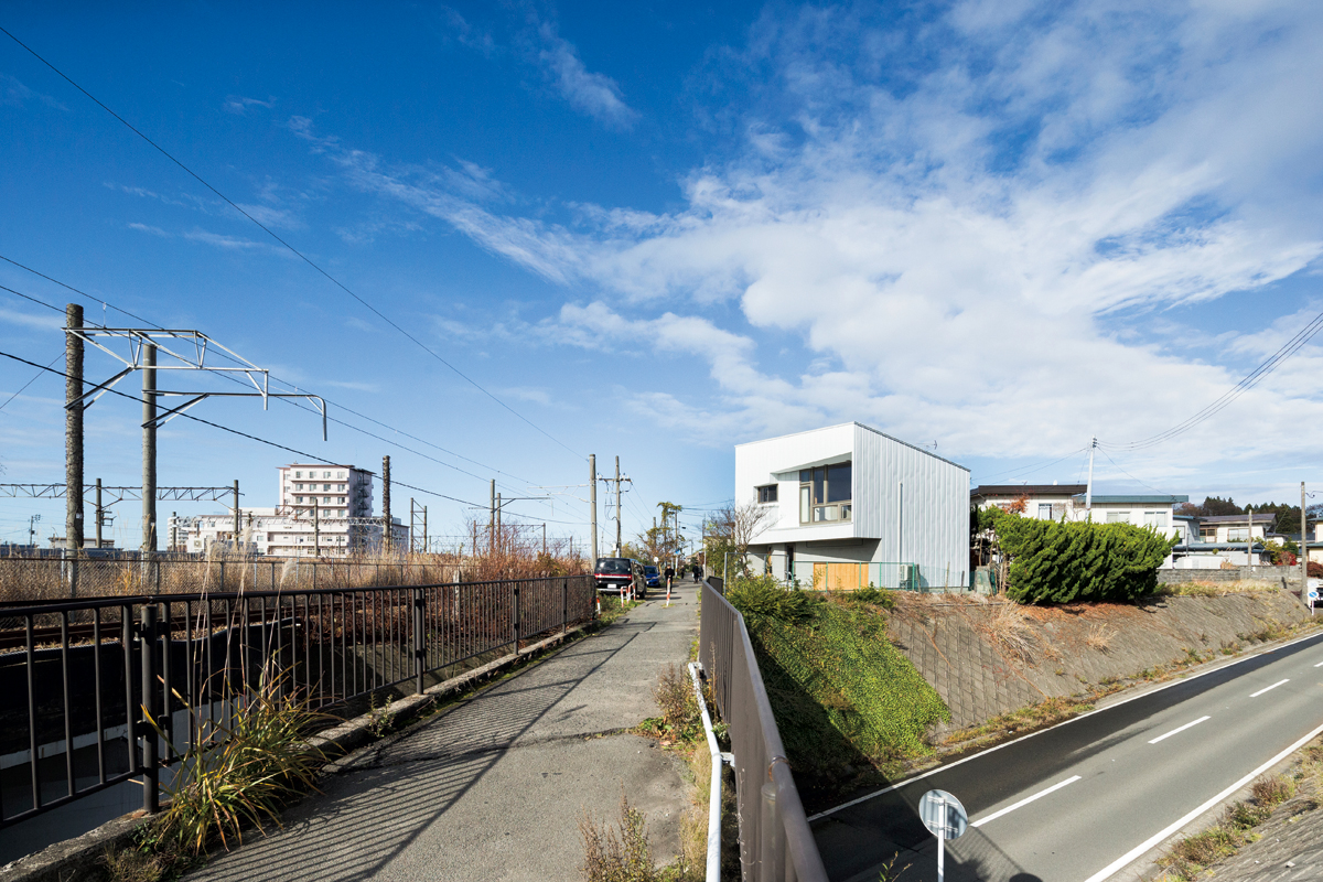 五角形の敷地に建つ不規則な四角形の家。外壁は玄関まわりはジョリパット、その他はガルバリウム鋼板仕上げ。中2階のリビングの床下は外物置とし、敷地に余裕のない狭小地のハンデをクリア