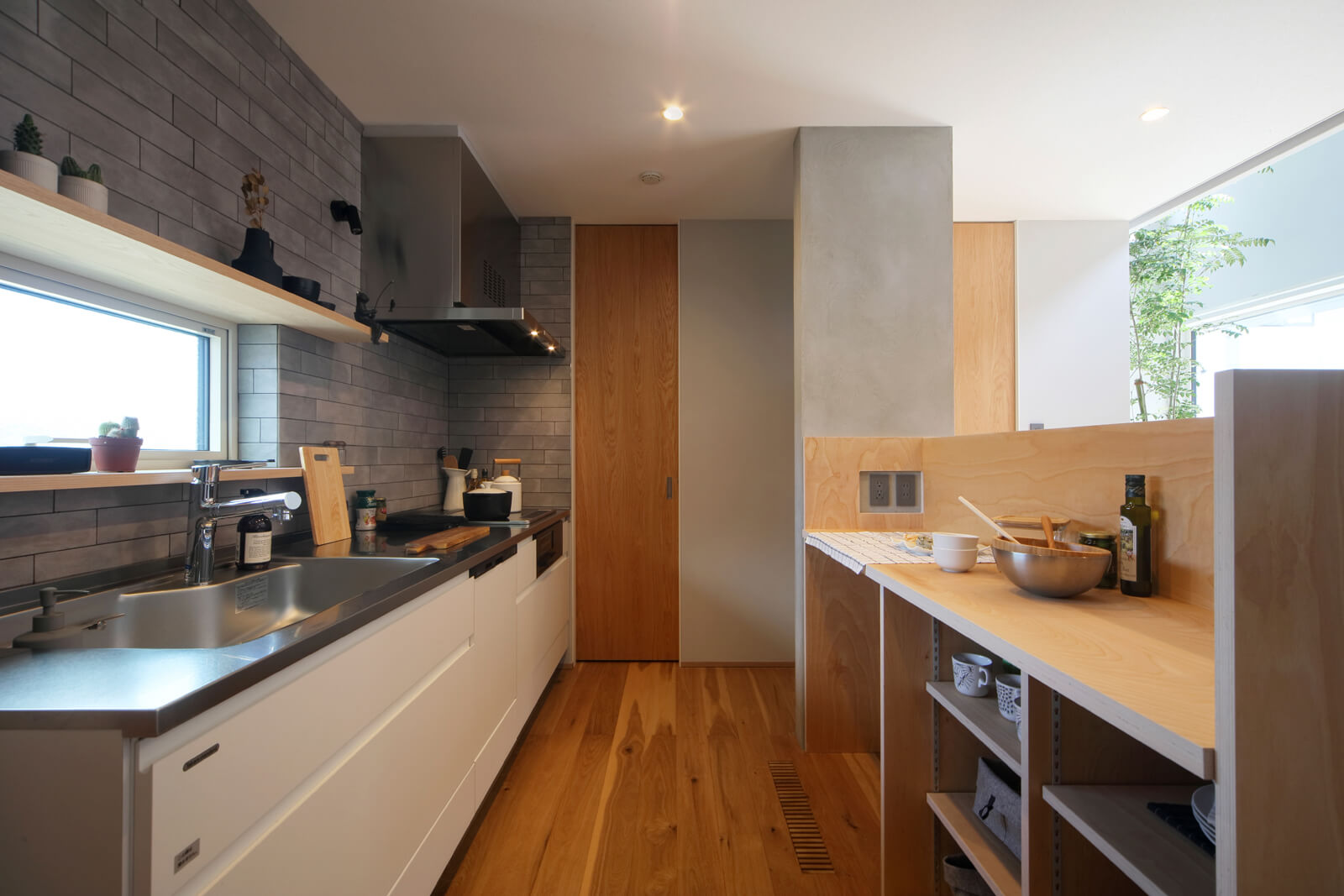 壁付けのキッチンと、独立した作業台で調理の効率をアップ。奥のドアは玄関収納に通じる