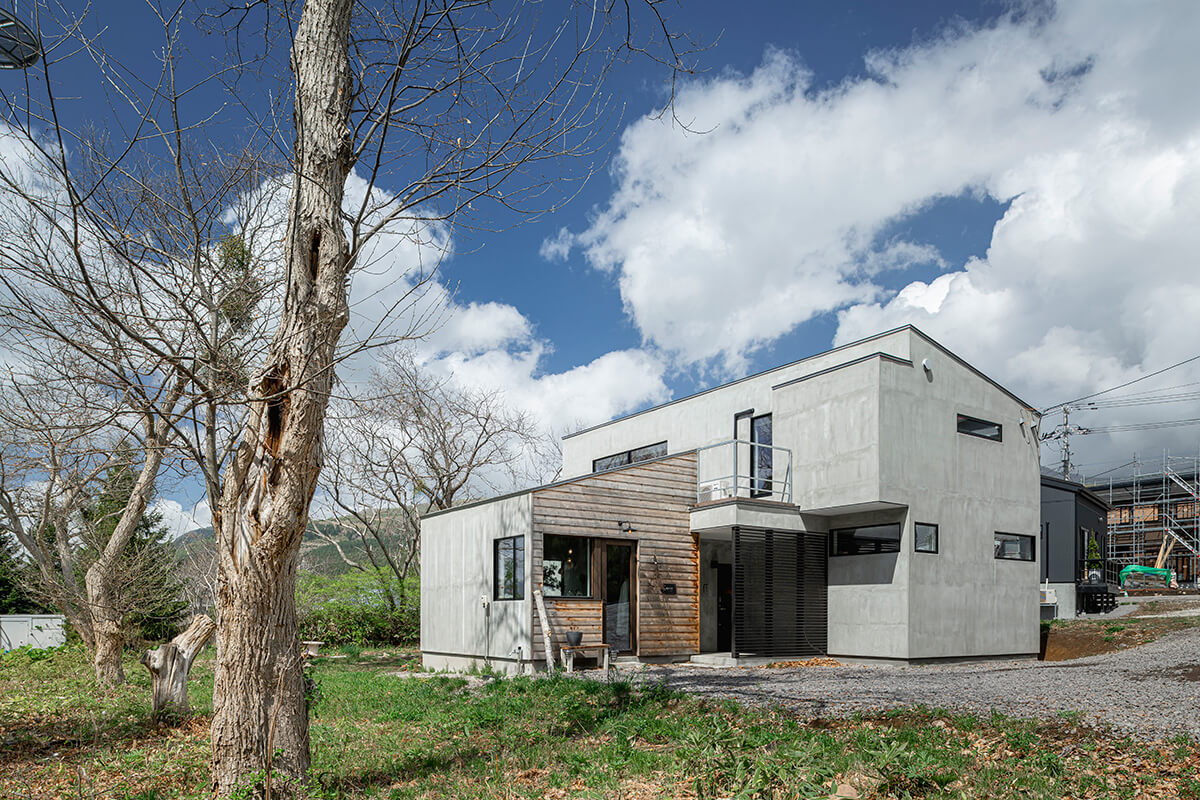 住居棟と店舗棟を左右に振り分け、片流れ屋根が遠景の山々のフォルムと重なって見えるような効果を意識してデザインされた店舗併用住宅