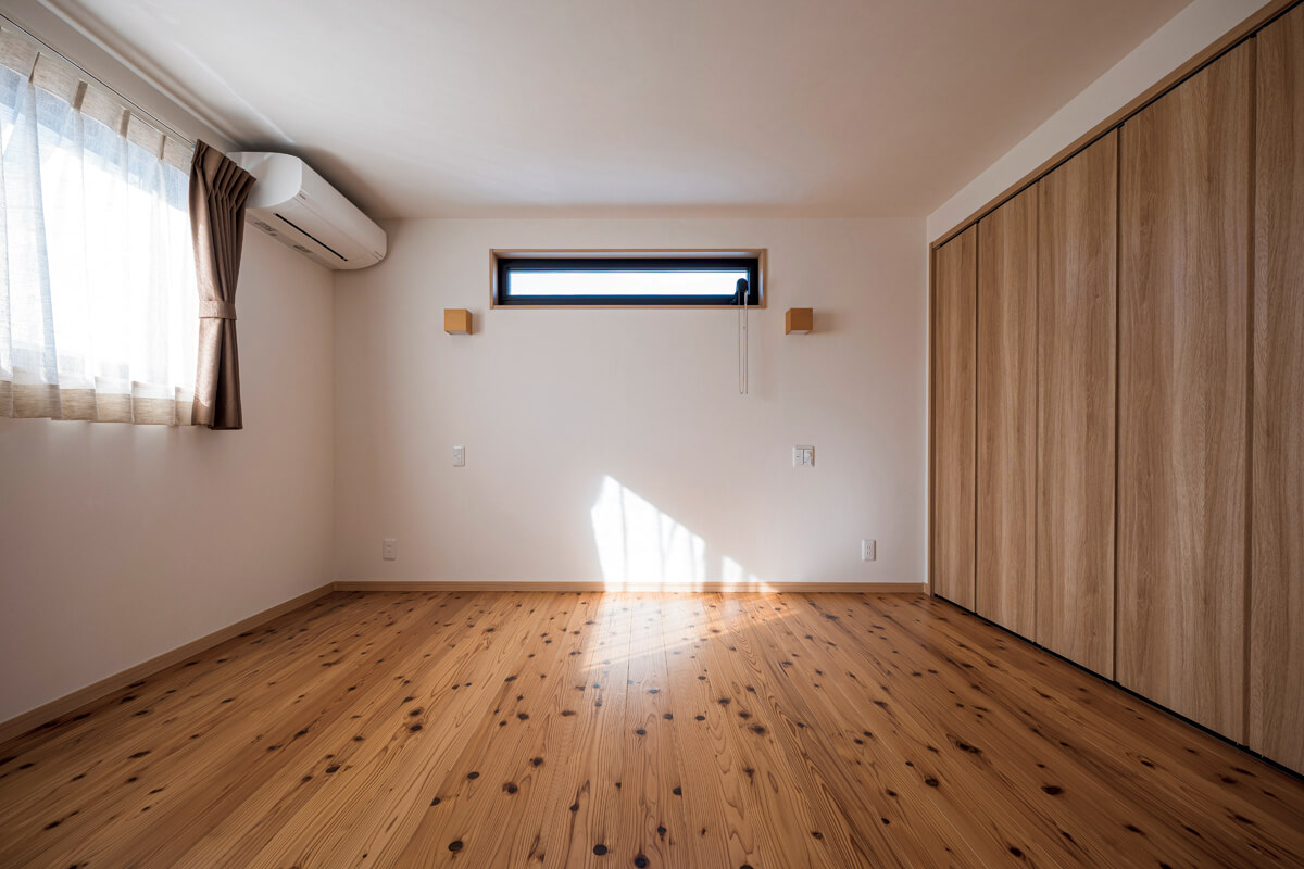 無垢の床と珪藻土の壁に囲まれた寝室。右手にはたっぷり収納できるクローゼットがある