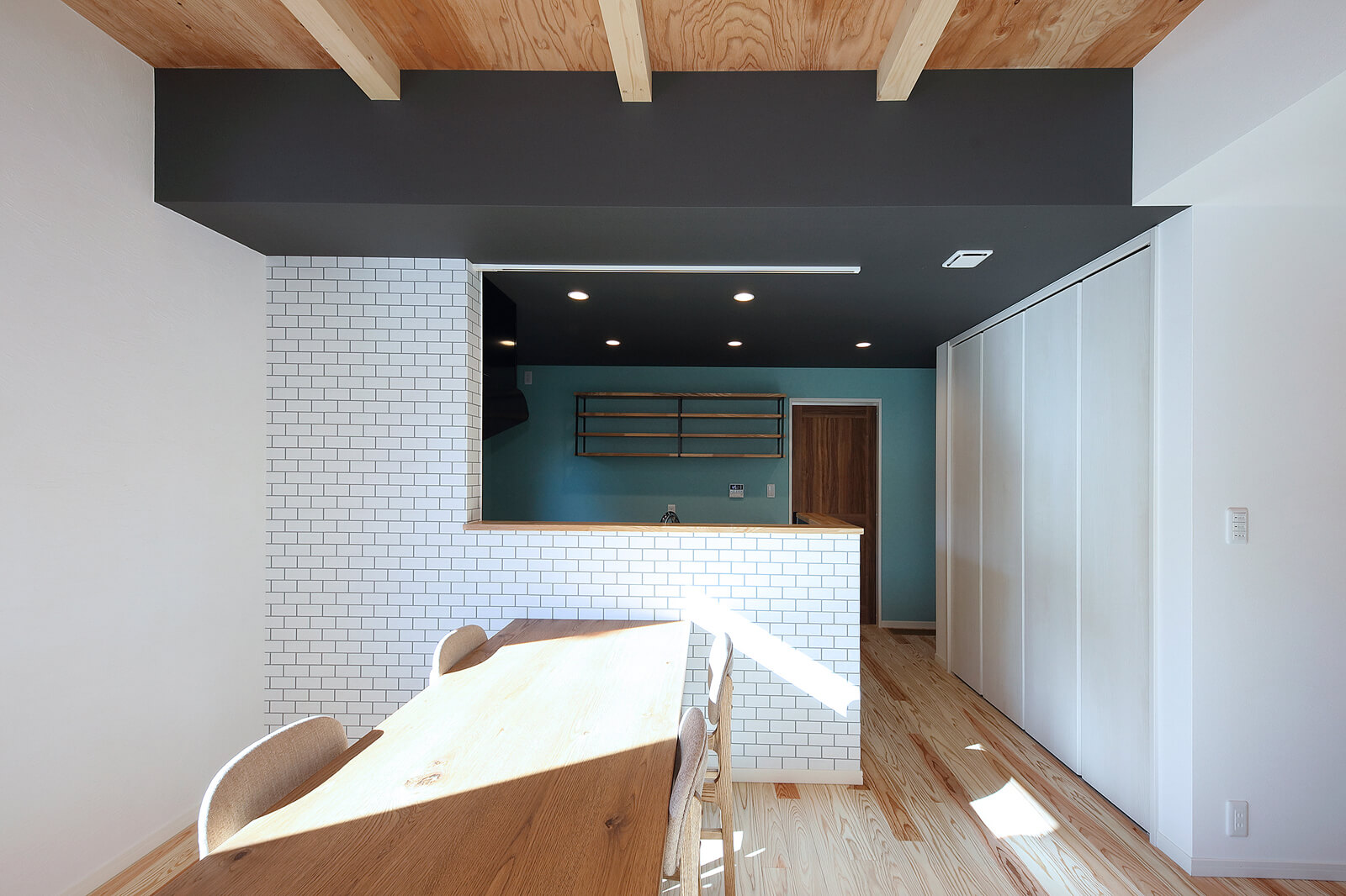 オビスギの床、ヒノキの天井など木質感が心地よいLDKは、キッチンの壁がアクセントになっている