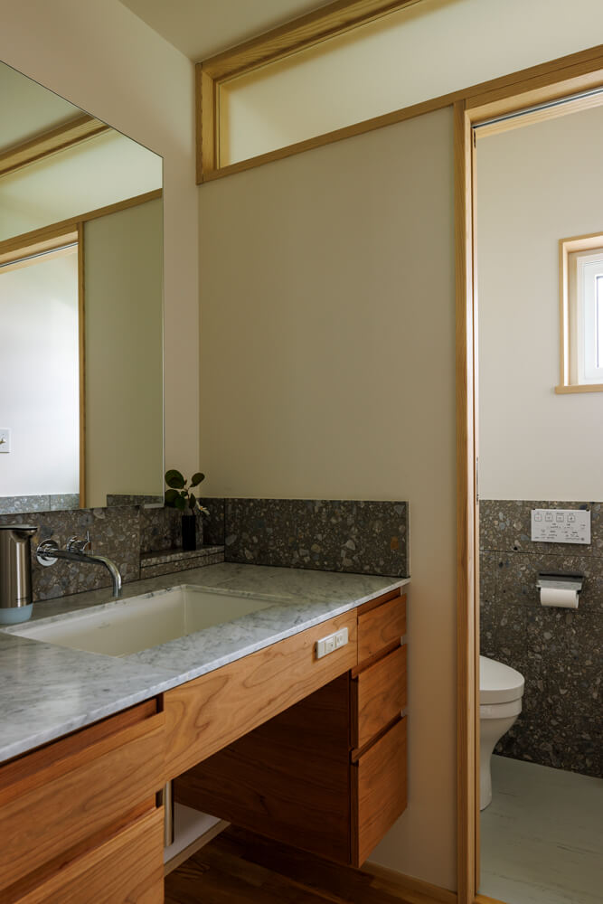 玄関ホールに配置した洗面台とトイレ。洗面台の壁面やトイレの腰壁にはキッチン同様テラゾを採用し、雰囲気を統一している