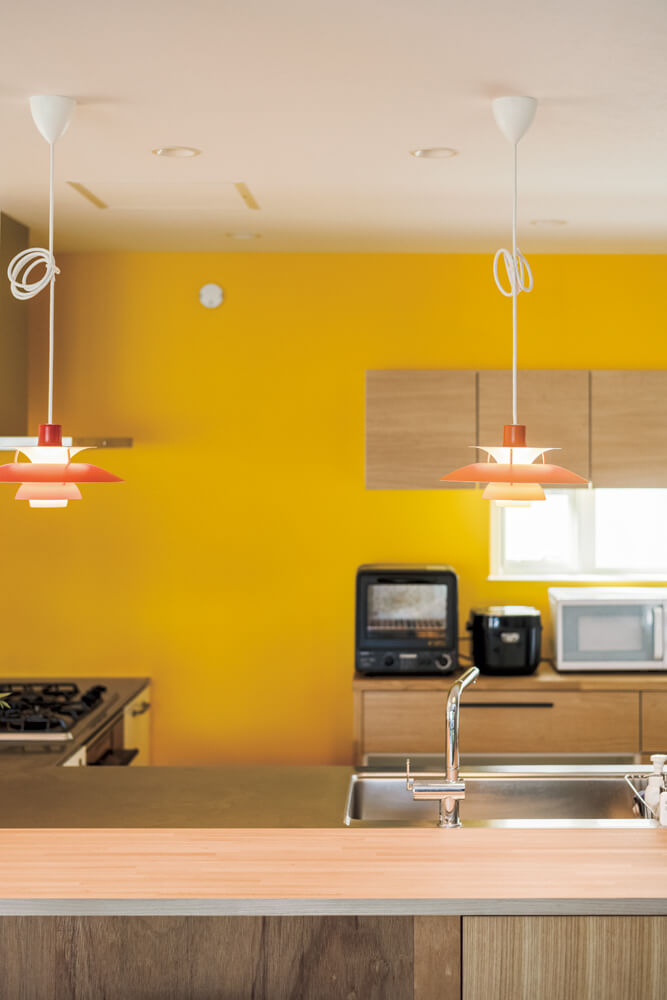 キッチンの壁には、ショールーム巡りの際に「好き」と感じた鮮やかな黄色のアクセントウォールを採用。カウンターの照明も色合いをそろえた