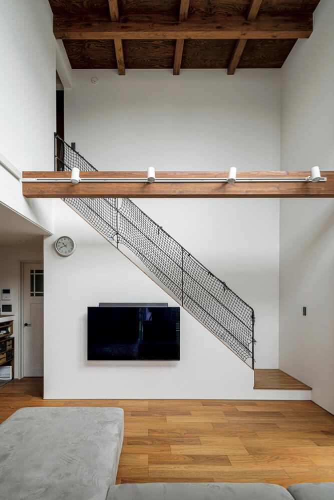 階段の手すり部分は壁仕様からスケルトンに変更した。格子状の現しの梁と針葉樹合板で、空間が映えるデザイン性の高い天井になっている