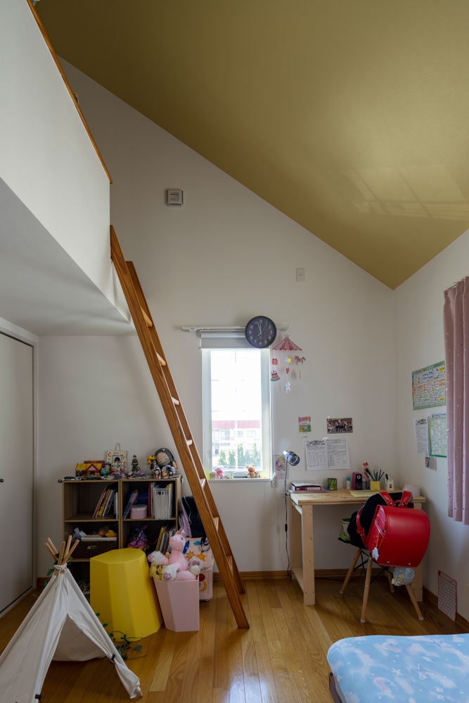 2階のロフト付き洋室は、子ども部屋として利用。屋根なり天井には、明るいマスタードカラーの壁紙を貼ってアクセントに