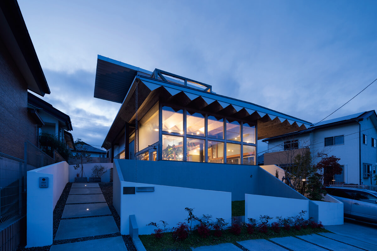夕映えのファサード。外と内をつなげる折形の屋根がより建物の存在を強調する