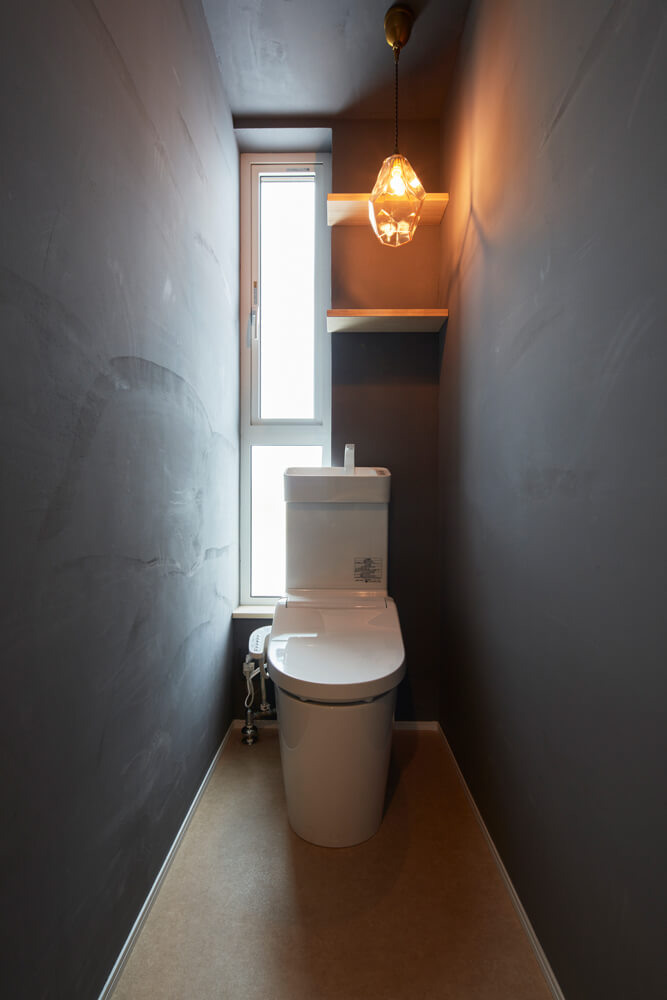 トイレも、シックなダークグレーの塗り壁。ペンダントライトの明かりが美しい印影を描く