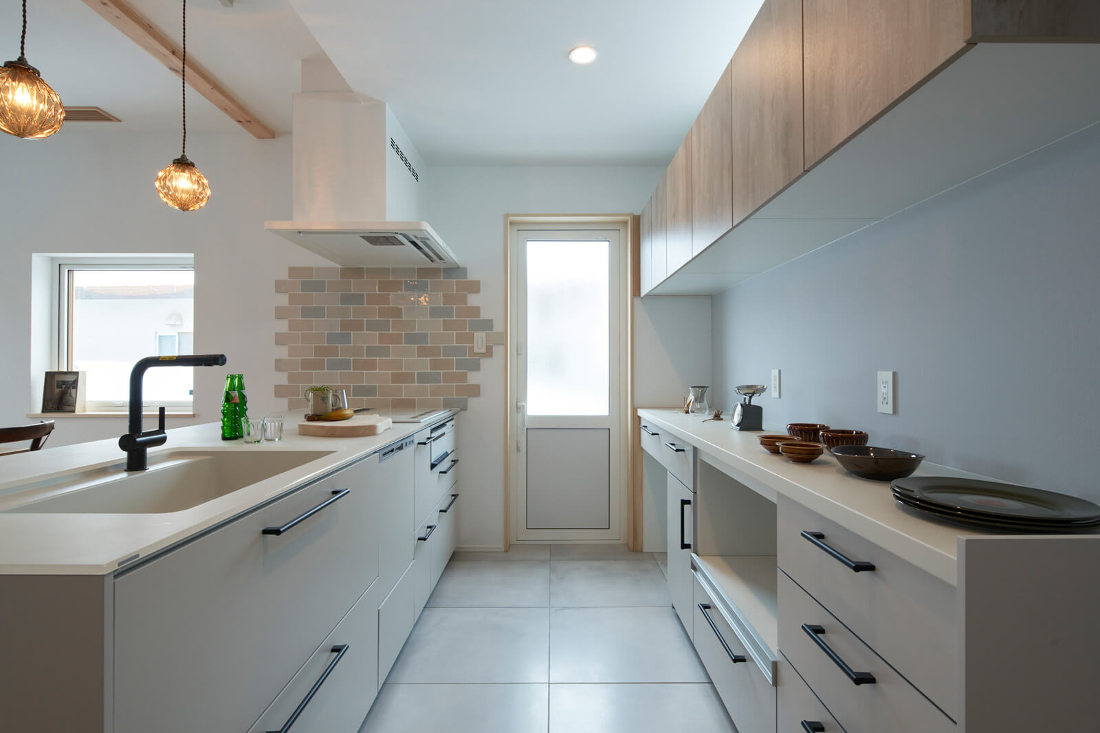幅を広く取ったキッチンは、ナチュラルな色味に加えテラスドアからの光でより明るい空間に