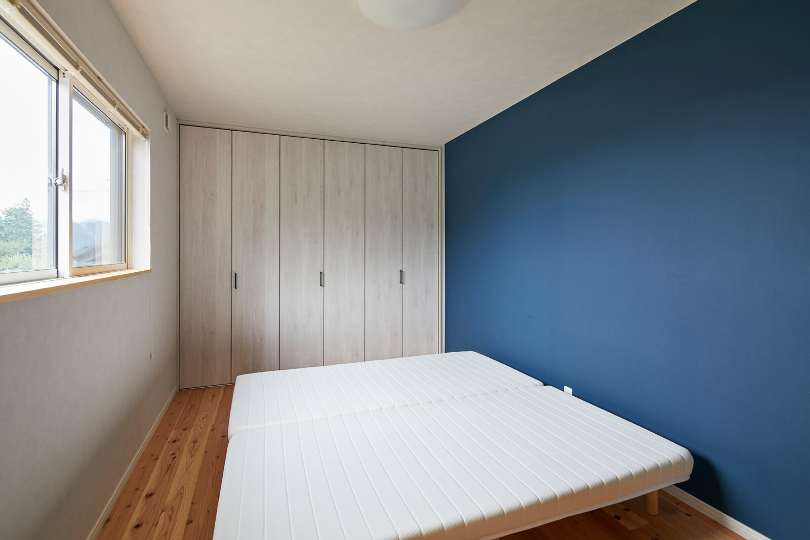 もとの廊下と和室の一部を一体化させて爽やかなブルーのアクセントウォールが映える寝室に。2階も間取りを大幅に見直した
