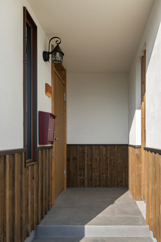 腰壁とタイル、アイアンの外灯がクラシカルな雰囲気を漂わせる玄関ポーチ
