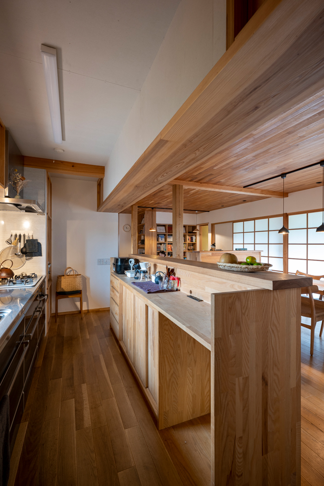 キッチンにも木をふんだんに使った造作がたっぷり。天井の素材や高さを変えることで変化を付けている