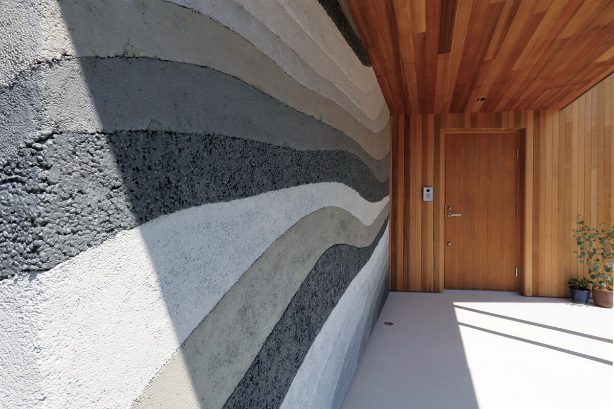 日本古来の版築壁をイメージし、一層一層土の調合を変えて造作された玄関ポーチの土壁。熟練した職人のなせる技だ