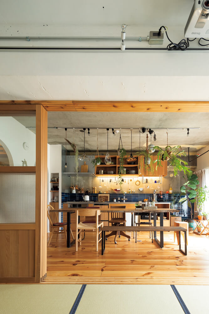 和室からはカフェのようなダイニング・キッチンが一望できる。キッチンの壁や畳の縁などところどころに用いた藍色と観葉植物が空間を優しく彩る