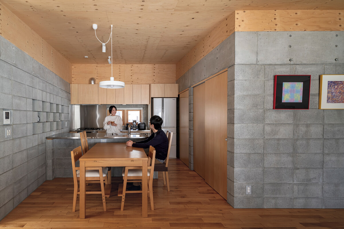 対面式のキッチンカウンターは天板の奥行きにゆとりを持たせた。ガスレンジは壁付けで配置。木とコンクリートブロックの優しい風合いが、家族団らんの空間を包む